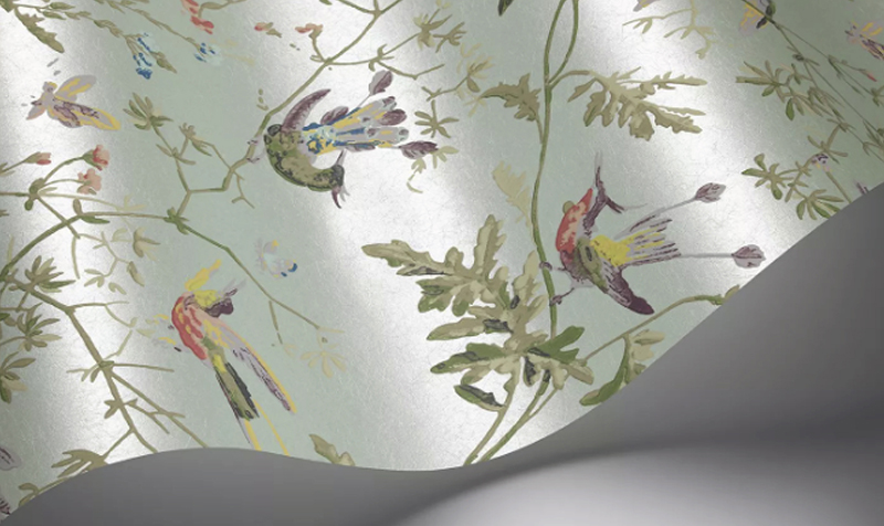 Cole & Son Hummingbirds blue bird wallpaper around a fireplace, with birds in flight across a soft coloured ground