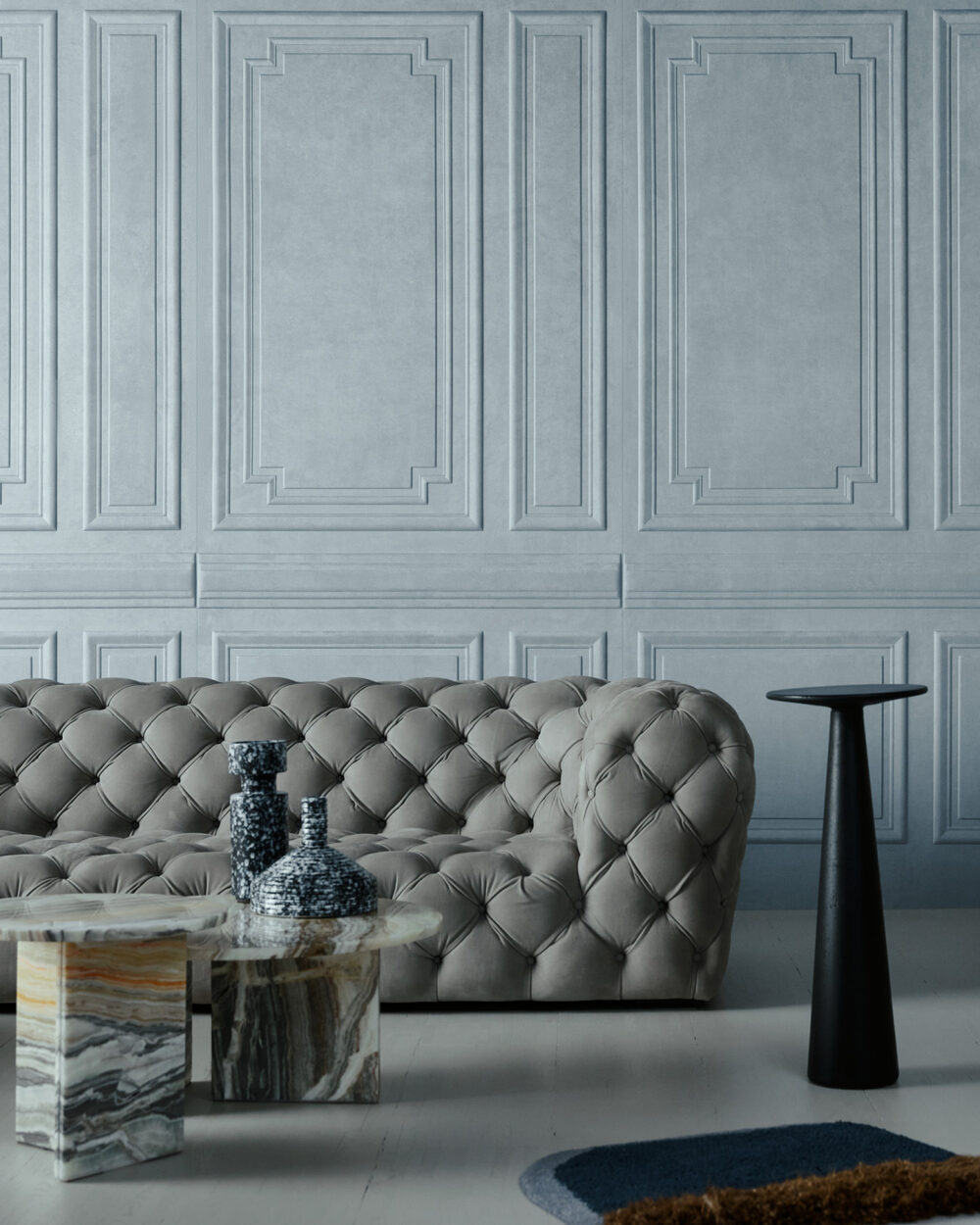 Arte ‘Grandeur’ panel-effect 3D wallpaper in Fog (44002) behind a tufted sofa