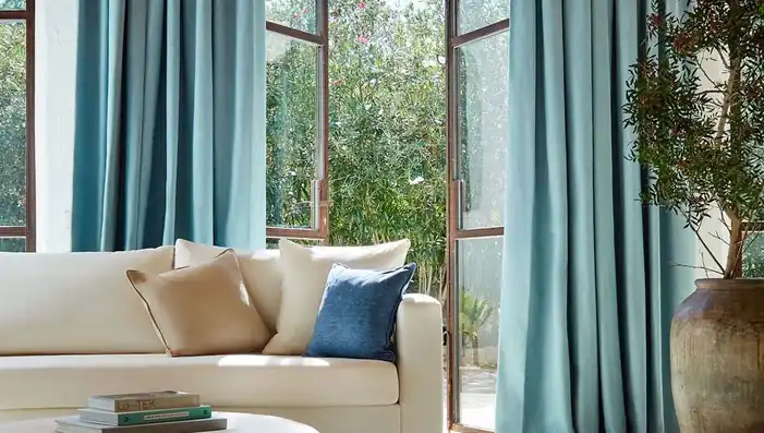 Turquoise curtains beside a cream sofa and open garden doors