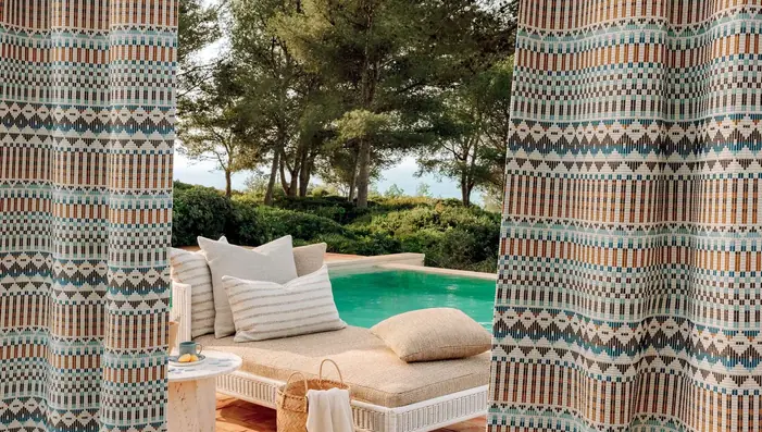Patterned outdoor curtains framing a sheltered poolside seating area