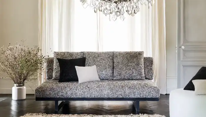 Grey textured sofa with black and white cushions in a light interior