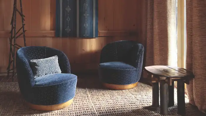Two navy blue upholstered chairs beside warm timber walls and brown curtains