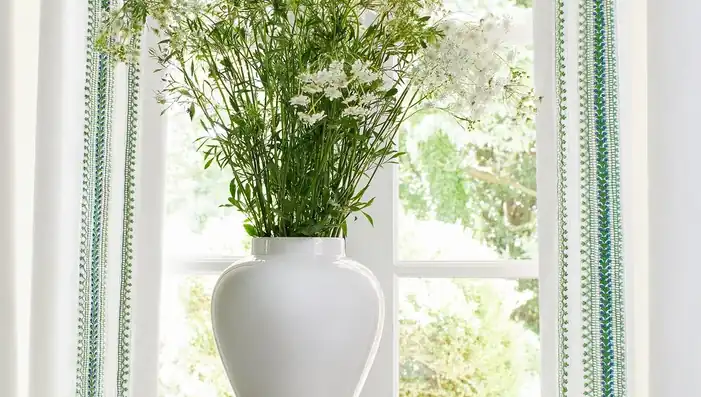 White curtains with green decorative tapes beside a window