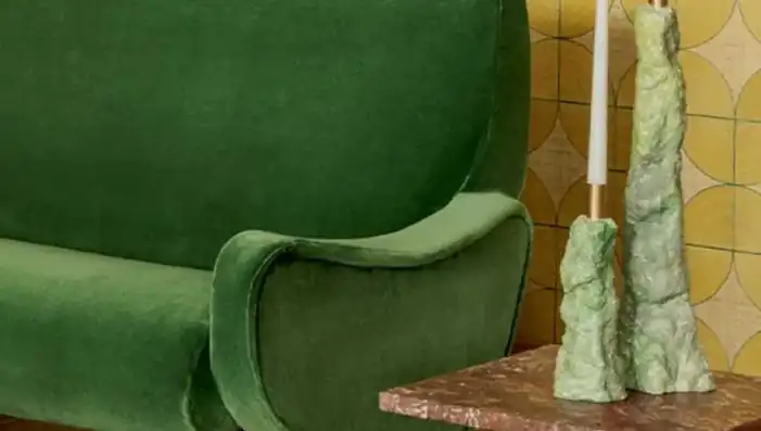 Green upholstered sofa against a yellow patterned wall