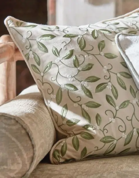 Cushion upholstered in Mistletoe Embroidery fabric by Morris & Co featuring green leaves and white berries
