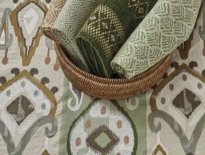 Assortment of green patterned textiles displayed on Turfan fabric by Nina Campbell featuring an ikat-inspired design