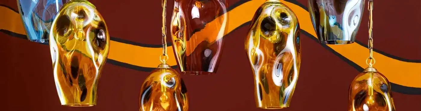 Colourful sculptural glass pendant lights against an orange patterned backdrop