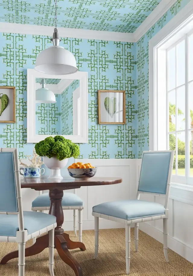 Green faux-bamboo lattice wallpaper in a bright dining room with blue chairs