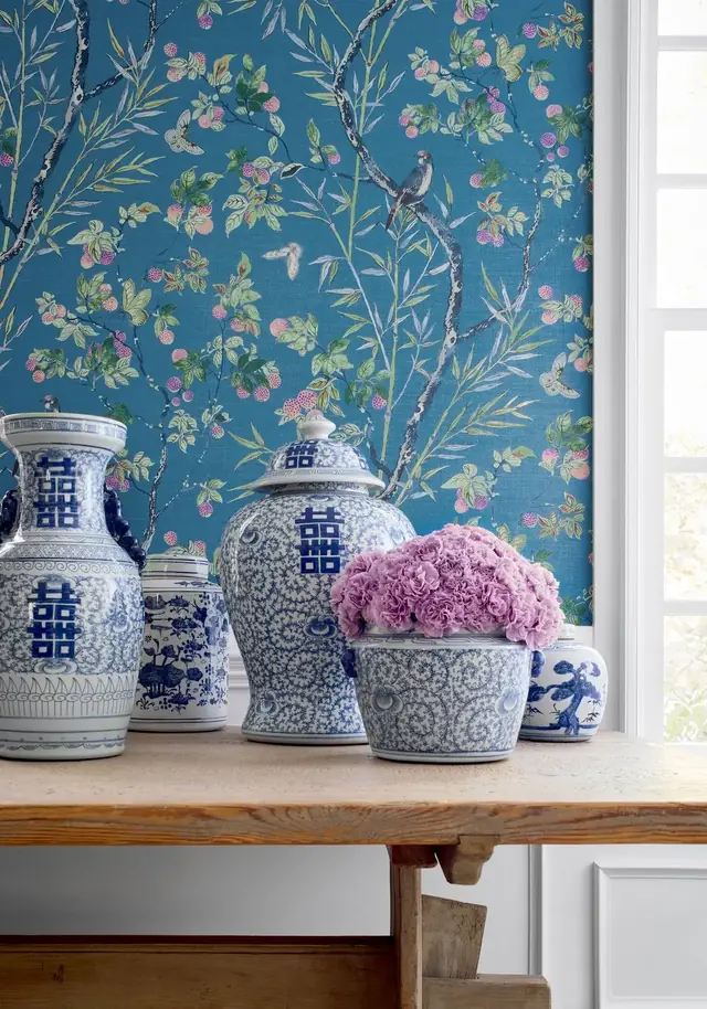 Navy wallpaper with birds, butterflies and slender flowering branches above a console table