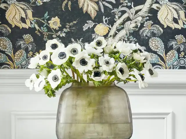 Black botanical wallpaper with pale flowers and foliage above panelling