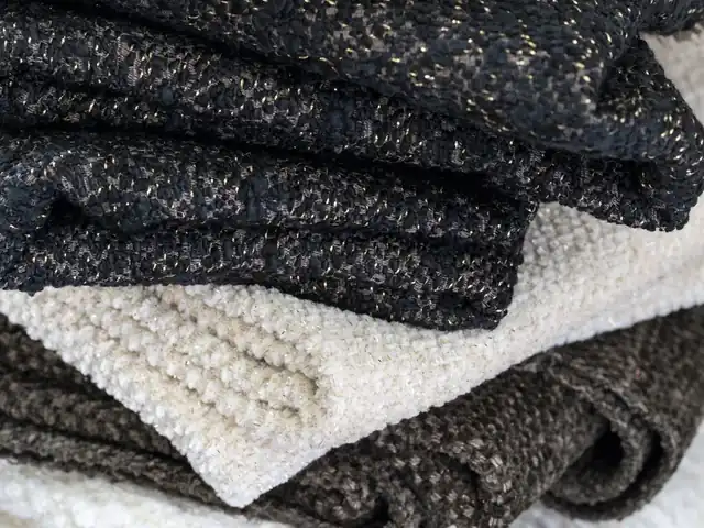 Stacked black, charcoal and cream fabrics showing contrasting woven textures