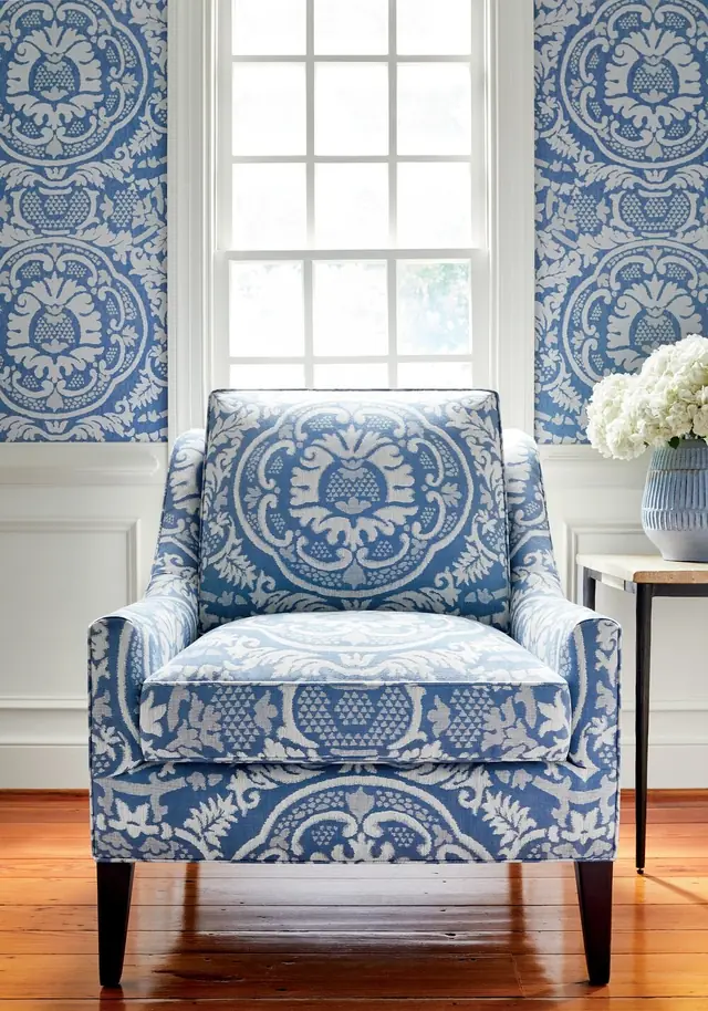 Blue damask curtains and a coordinating upholstered armchair in a light interior