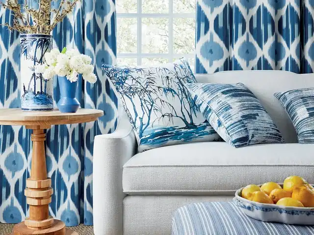 Blue and white patterned curtains and cushions with a striped upholstered ottoman