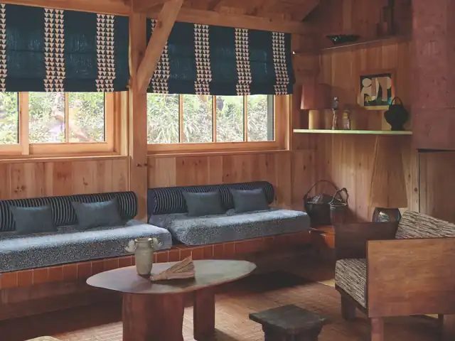 Blue patterned Roman blinds above a window seat with blue cushions and striped bolsters