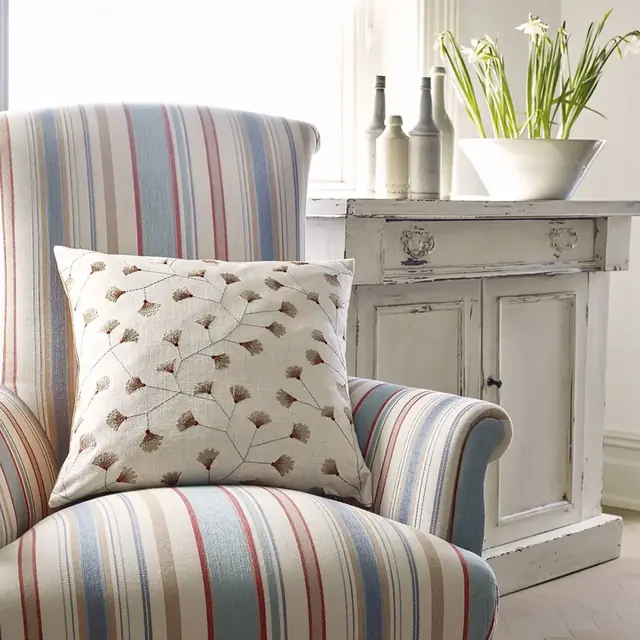 Blue and white striped fabrics used across a sofa, ottoman and cushions