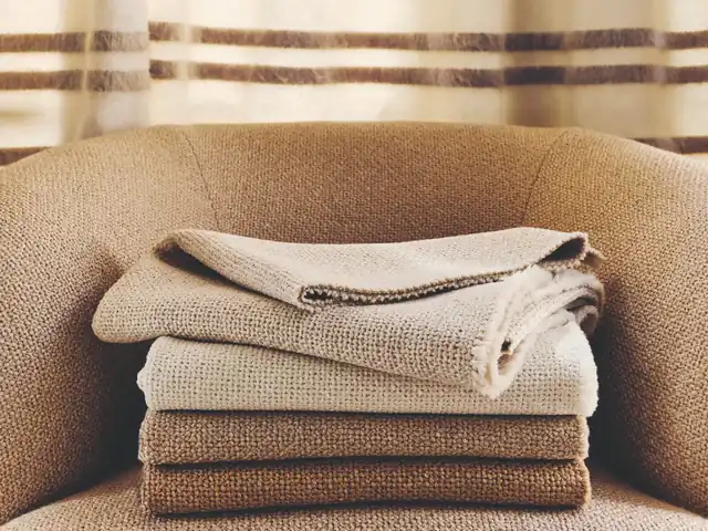 Folded brown, tan and cream fabrics arranged on an upholstered chair