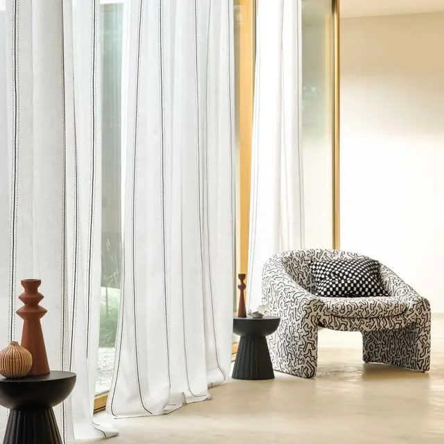 Camengo Odyssee sheer curtain fabric filtering daylight at a full-height window