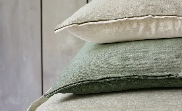 Layered cushions displaying neutral and green chenille fabric textures