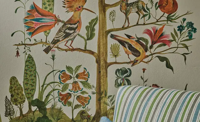 Colourful Christopher Farr Cloth botanical wallcovering behind a striped chair