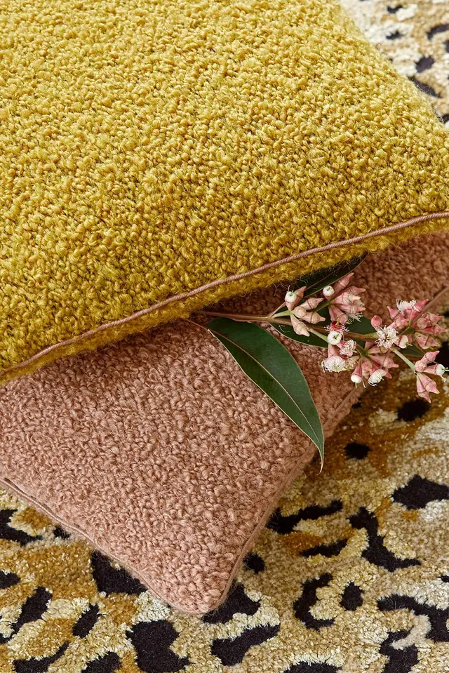 Layered cushions in mustard, blush and neutral bouclé upholstery fabrics