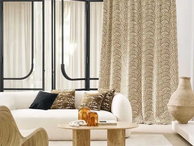 Cream and beige patterned curtains behind pale seating and a stone table