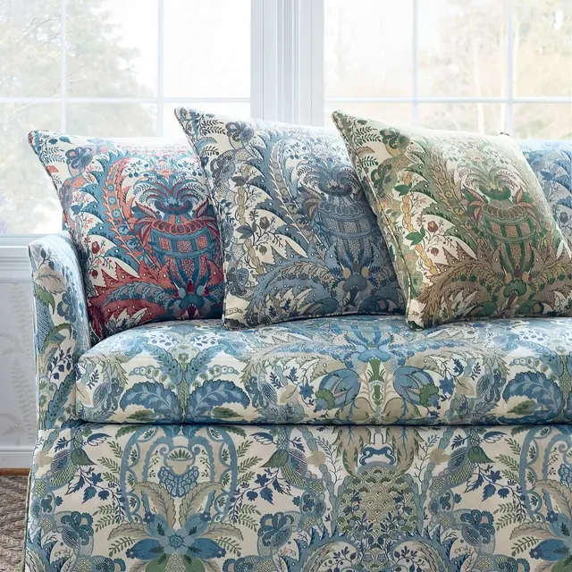 Blue, red and green damask fabrics arranged on a sofa with coordinating cushions