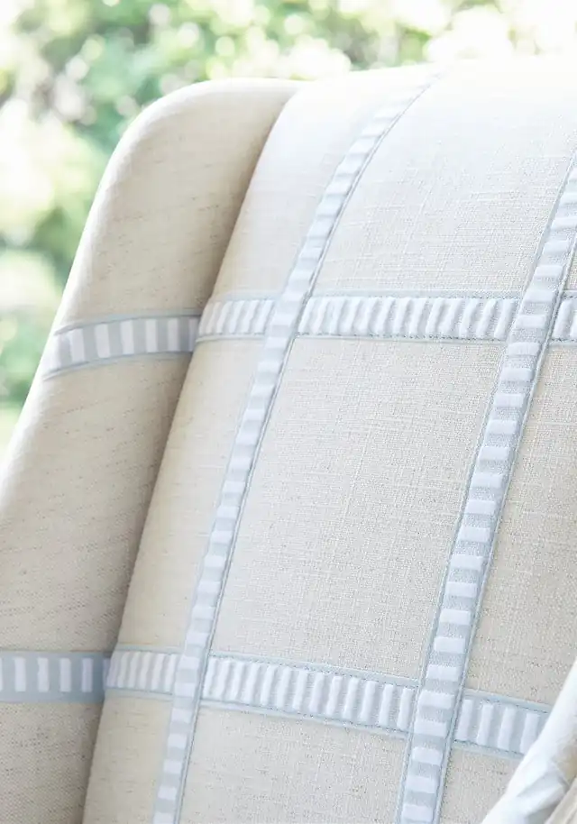 Pale blue and white decorative tape forming bands across a neutral upholstered chair