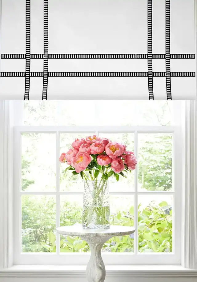 White Roman blind framed with black and white decorative tape