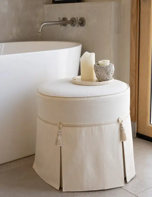 Cream upholstered stool decorated with individual tassels