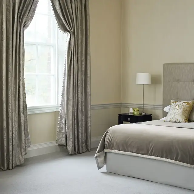 Silver silk-blend curtains with a full drape in an elegant bedroom