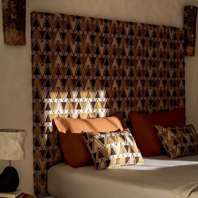 Geometric embroidered fabric used on a bedroom headboard and cushions