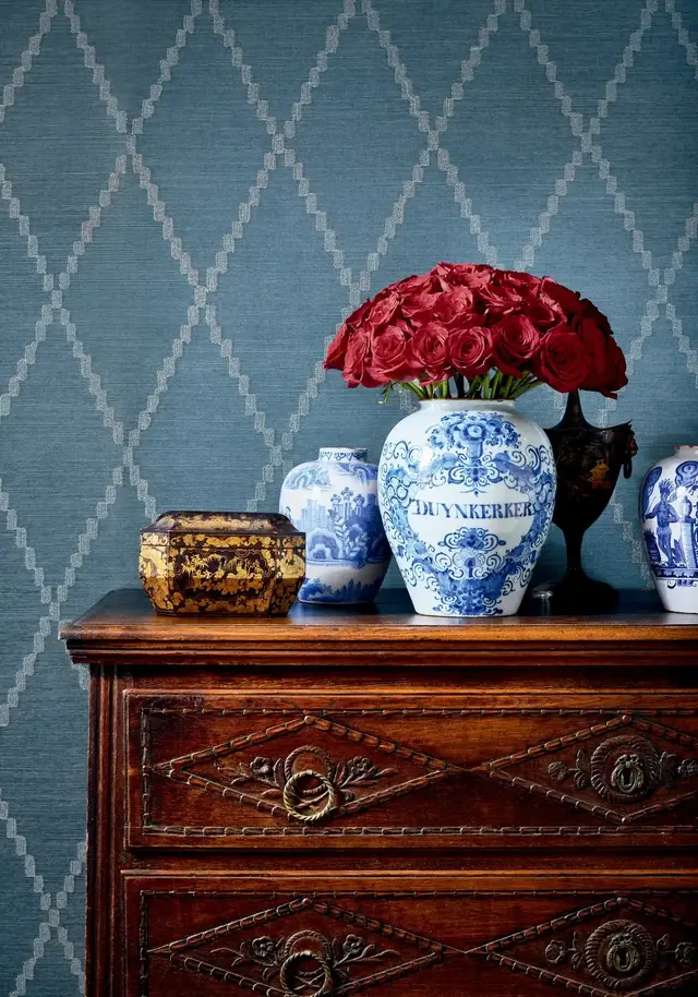 Navy sisal trellis wallpaper embroidered with luminous ribbon above an antique chest