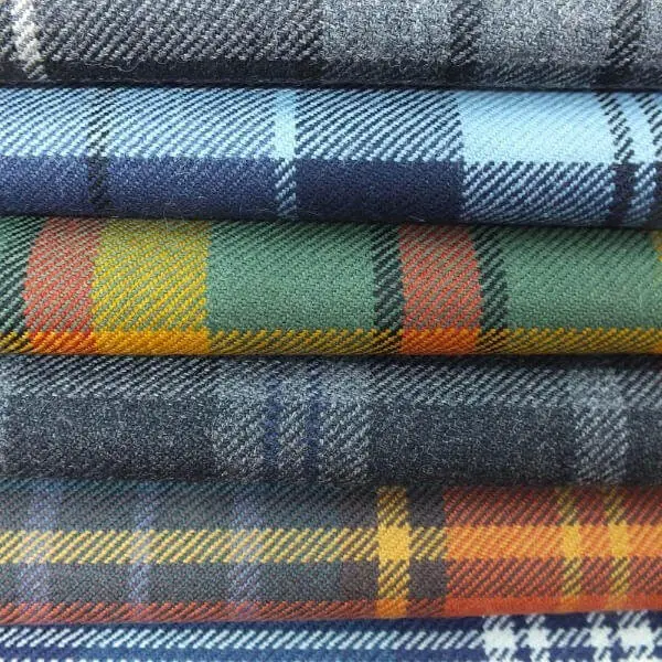 Stack of tartan fabrics showing crossing horizontal and vertical coloured stripes