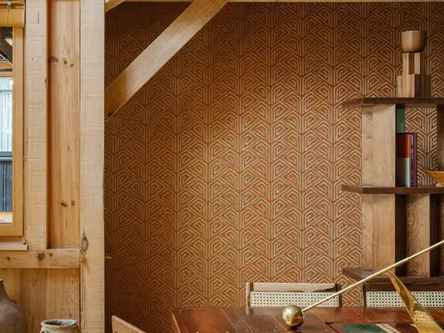 Orange geometric embroidery worked over a natural wallcovering in a timber interior