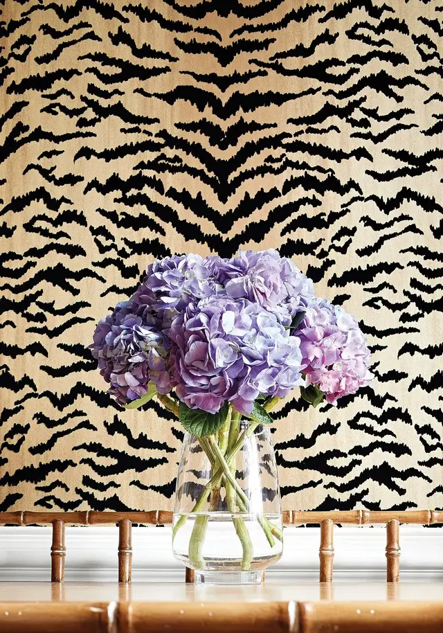 Gold and black tiger stripe flock wallpaper displayed with purple hydrangeas