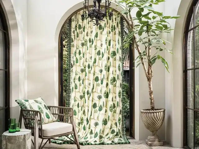 Green botanical curtains at an arched window beside a coordinating chair