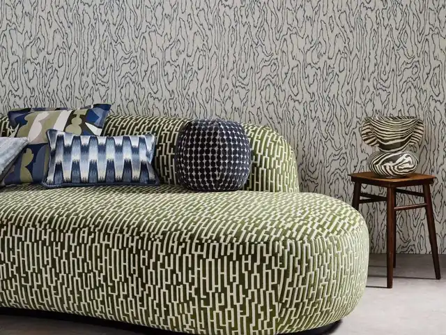Curved sofa in green and cream patterned fabric with contrasting cushions