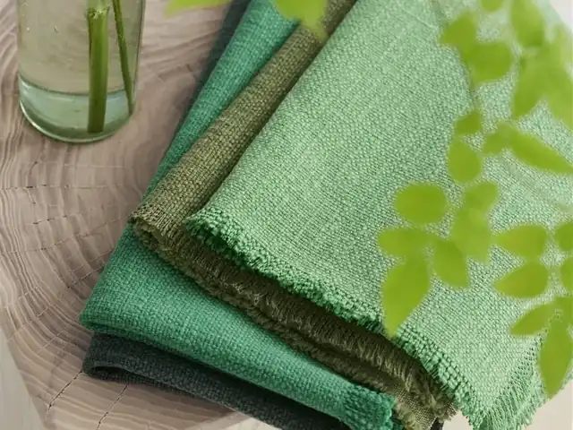 Layered green fabric samples showing different shades and woven textures