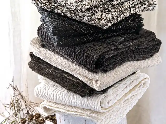 Folded grey, black and white fabrics showing contrasting woven textures