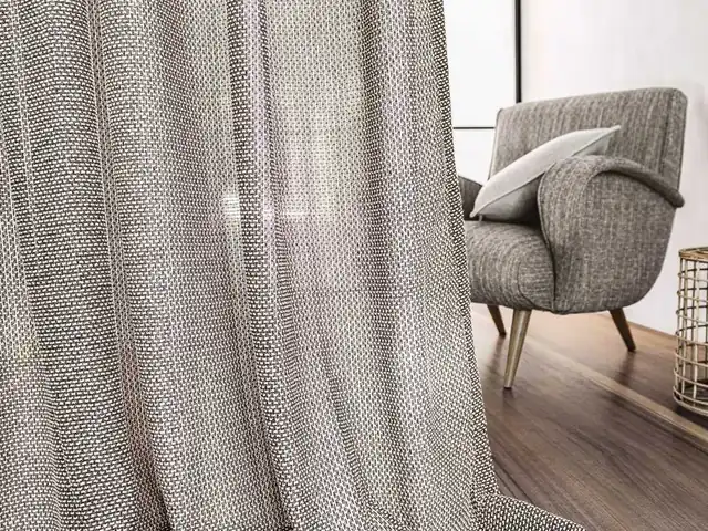Full-length grey textured curtains beside an upholstered chair