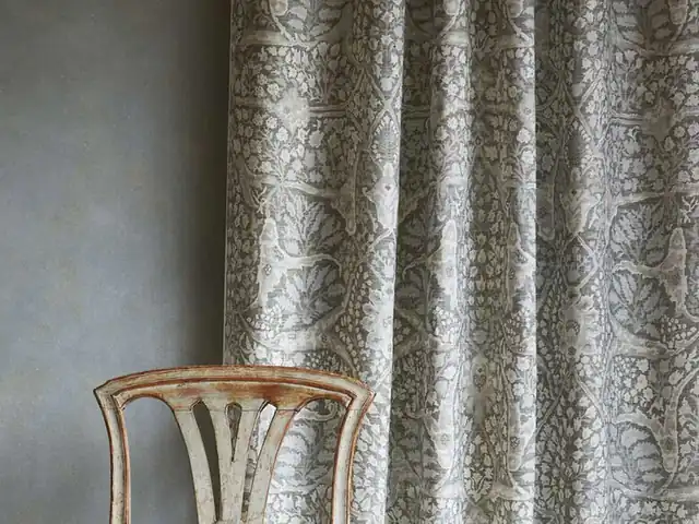 Grey patterned curtains beside a grey wall and wooden chair
