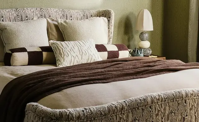 Upholstered headboard and cushions in coordinated Harlequin patterns and textures