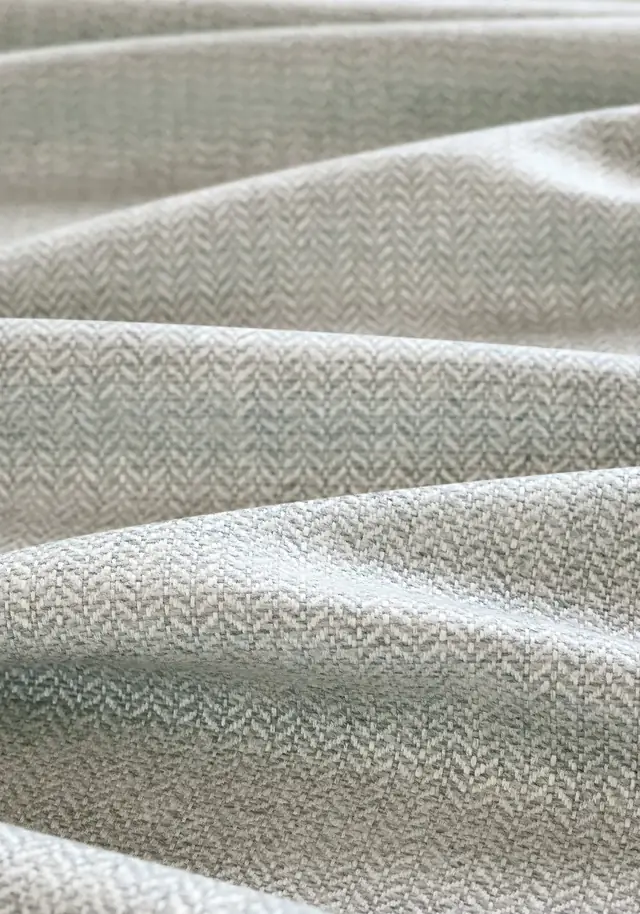 Grey herringbone fabric arranged in soft folds