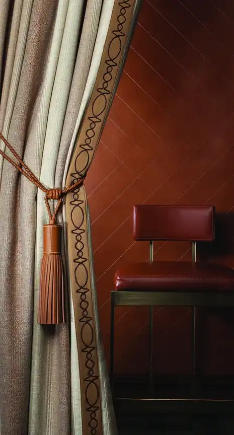 Tan leather tassel tieback with braided cords on a patterned curtain
