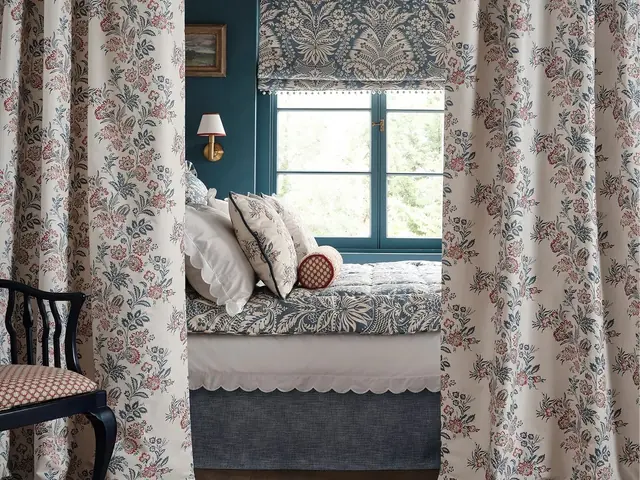 Roman blind with coordinating floral curtains in a layered bedroom interior