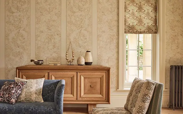 Morris and Co wallpaper, patterned furnishings and Roman blind in an interior