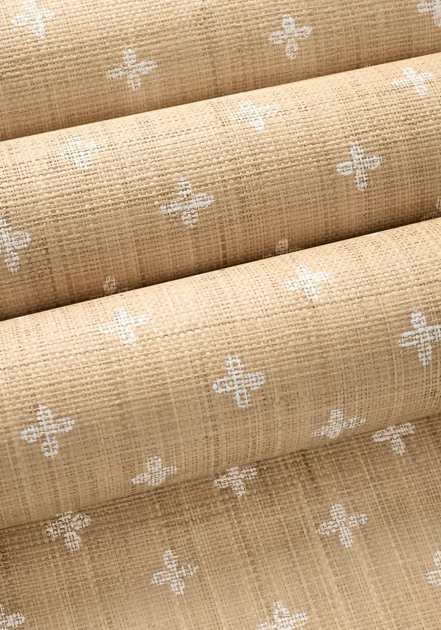 Rolls of natural textured wallpaper showing small white repeating motifs