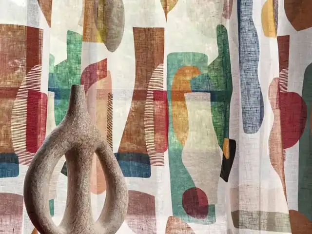 Curtain fabric with overlapping shapes in muted pink, green and ochre tones