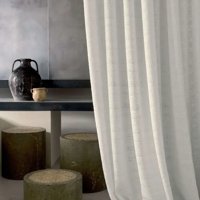 Natural linen curtain fabric falling in soft full-length folds