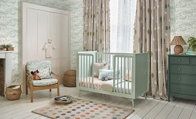 Neutral nursery with patterned curtains, a cot and soft upholstered accessories